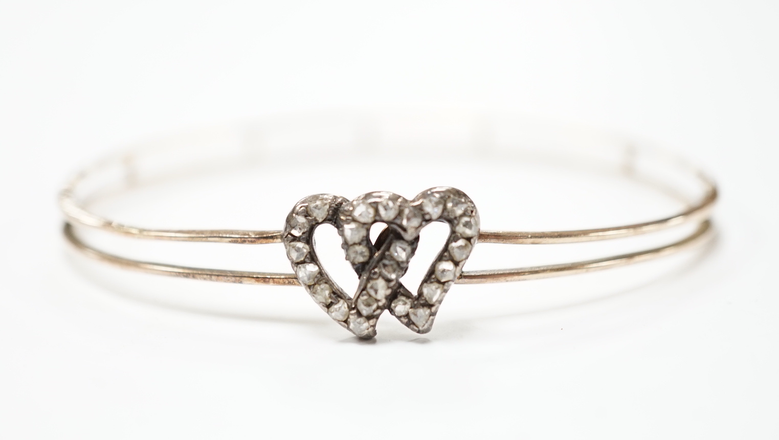 A late Victorian yellow metal and rose cut diamond set twin hearts bangle, gross weight 6.8 grams.